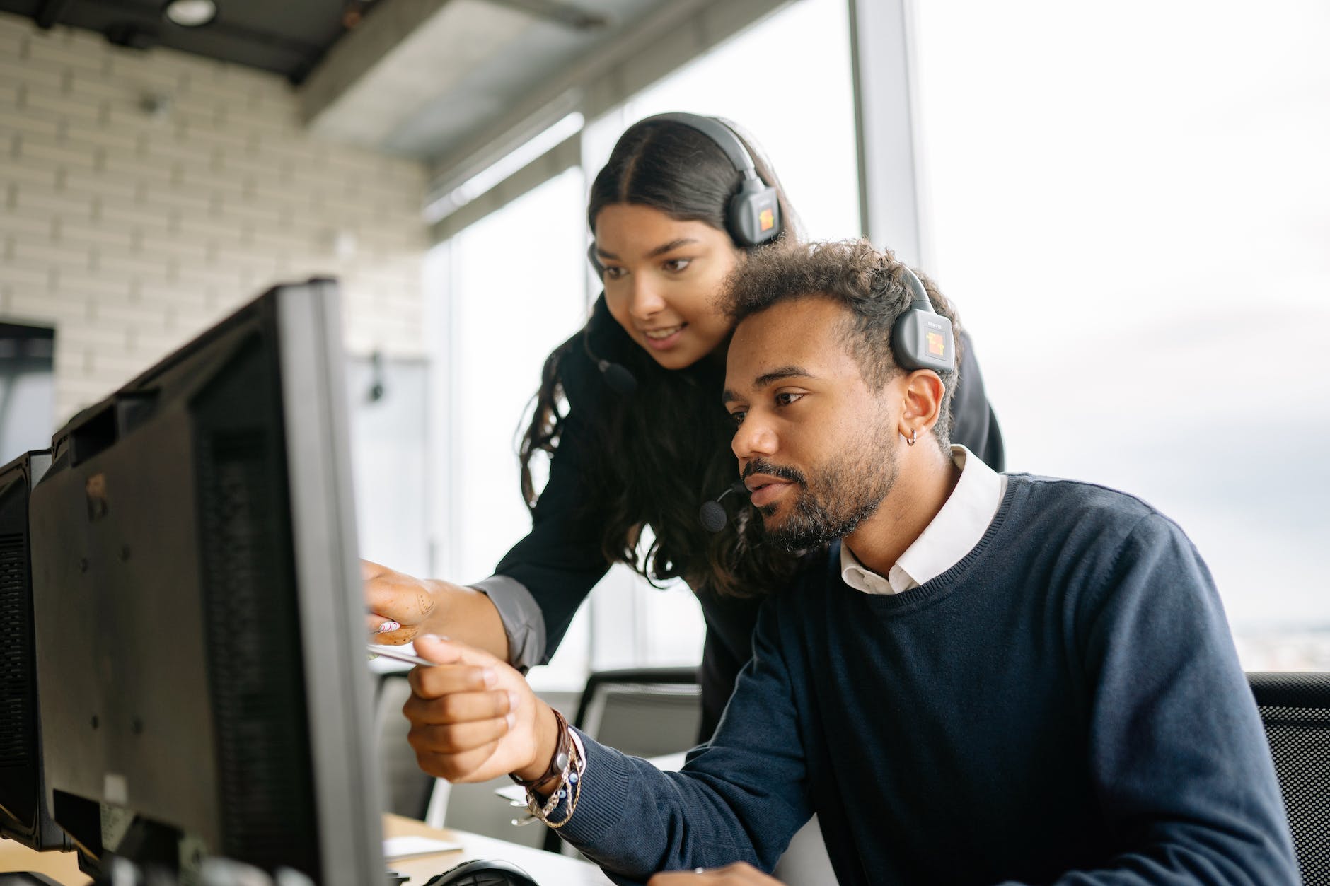 a man and a woman pointing at the computer screen